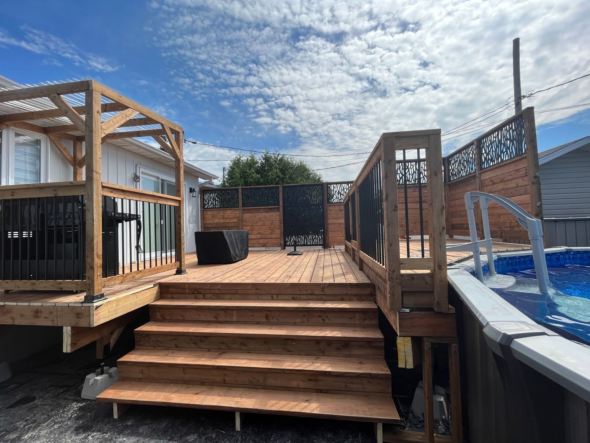 Une terrasse en bois avec escalier menant à une piscine.