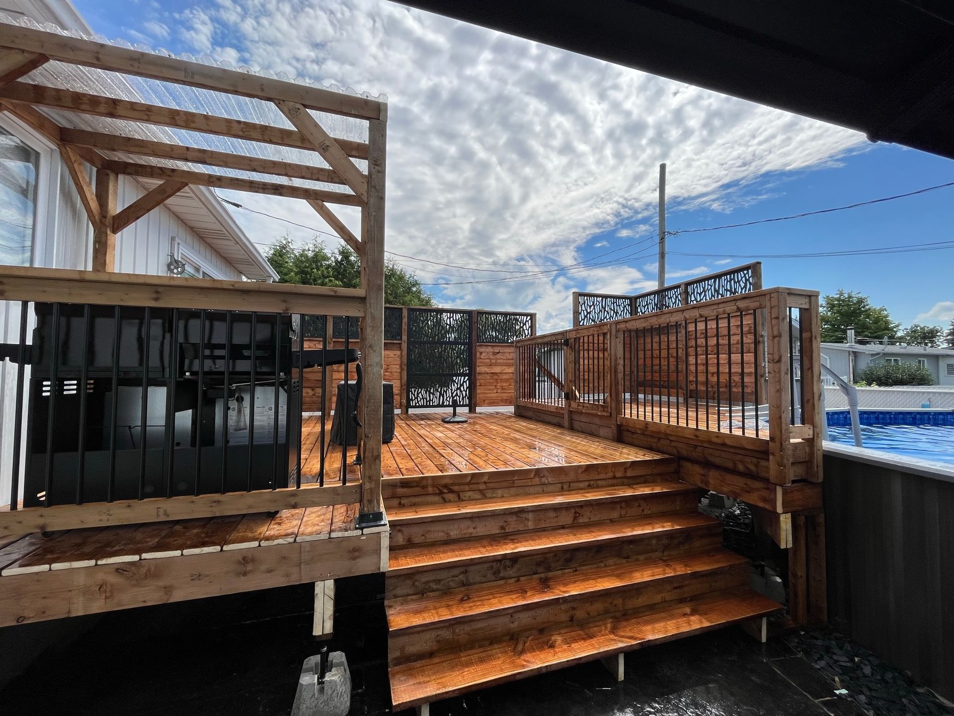 Une terrasse en bois avec des escaliers qui y mènent à côté d'une piscine.
