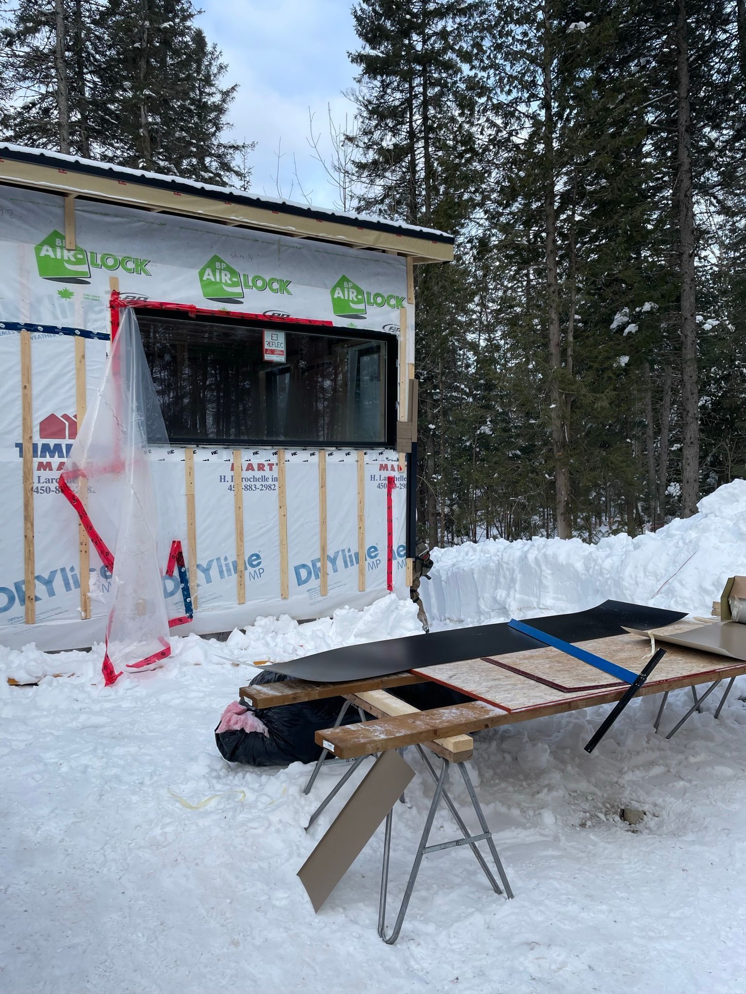 Une table en bois est posée devant un bâtiment couvert de neige.