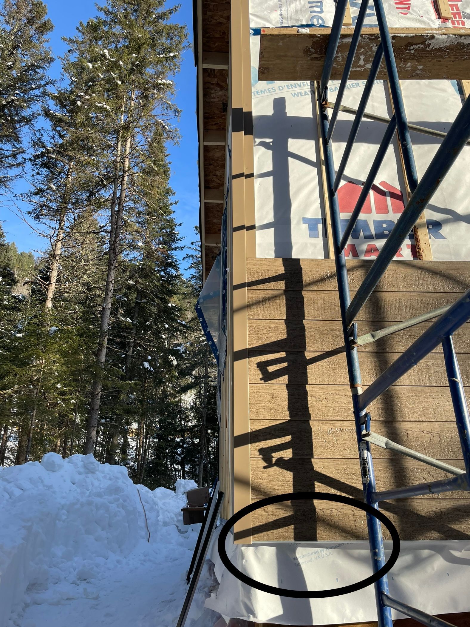Un échafaudage est posé sur le côté d'un bâtiment dans la neige.