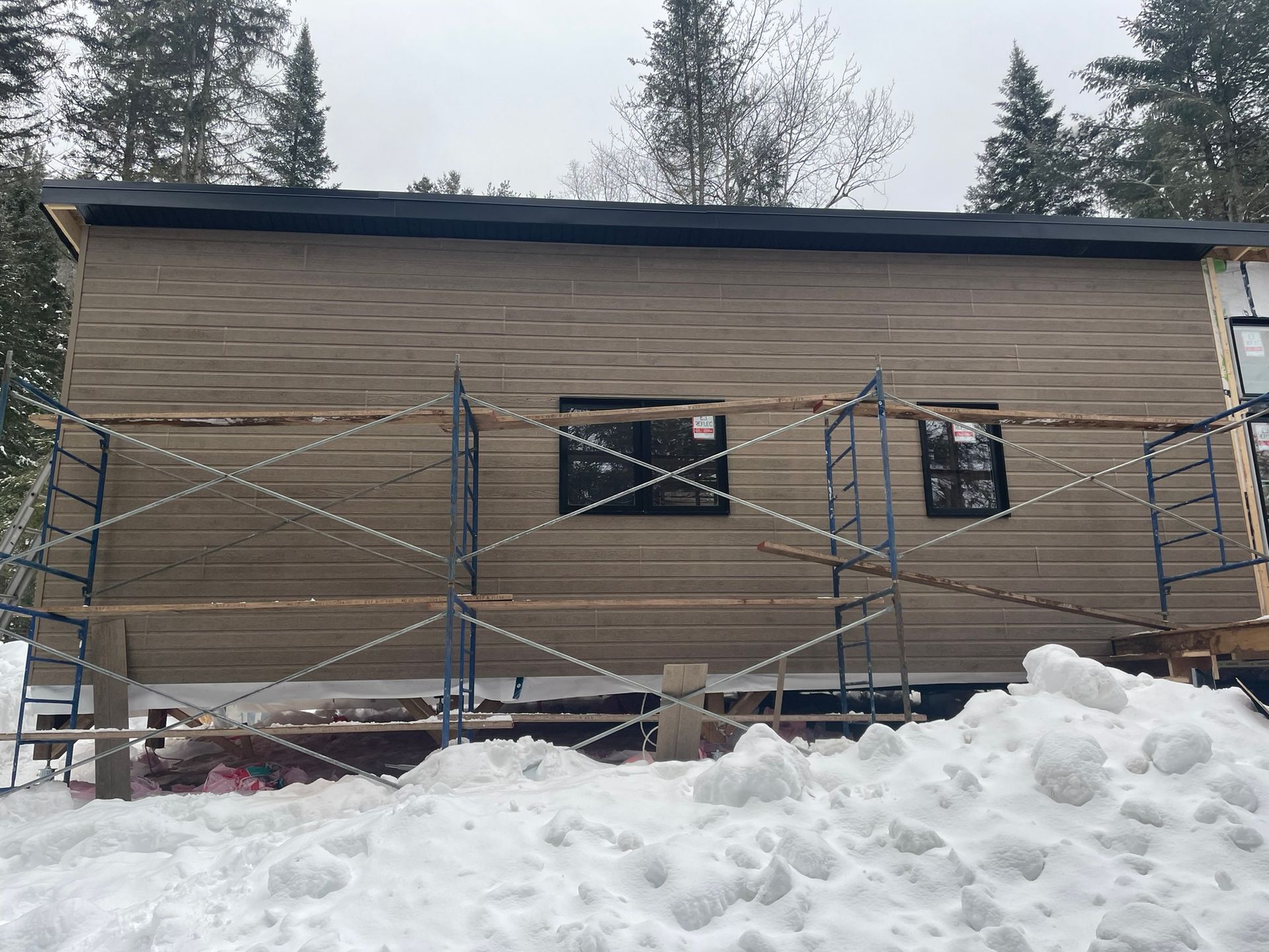 Une maison est en train d'être construite dans la neige avec des échafaudages autour.