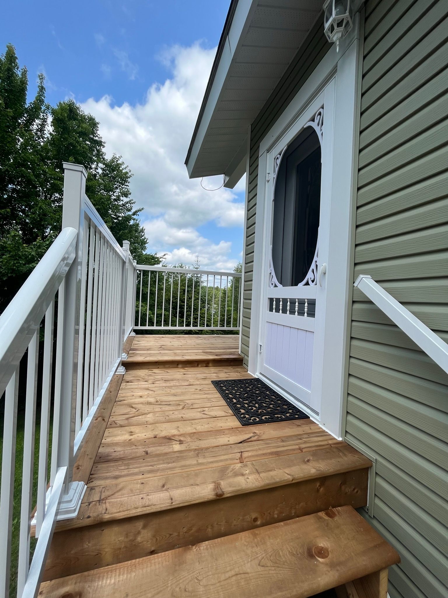 Une terrasse en bois avec des escaliers menant à la porte d'entrée d'une maison.