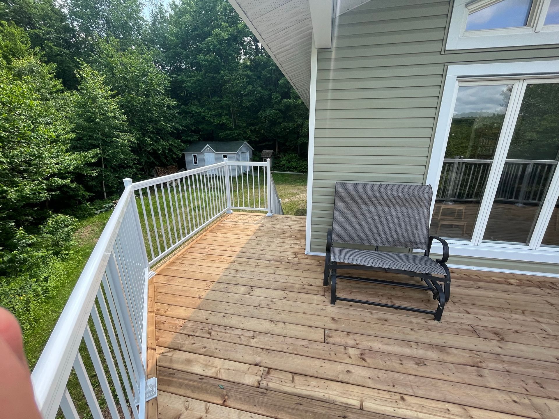 Une terrasse en bois avec une chaise et une table à côté d'une maison.