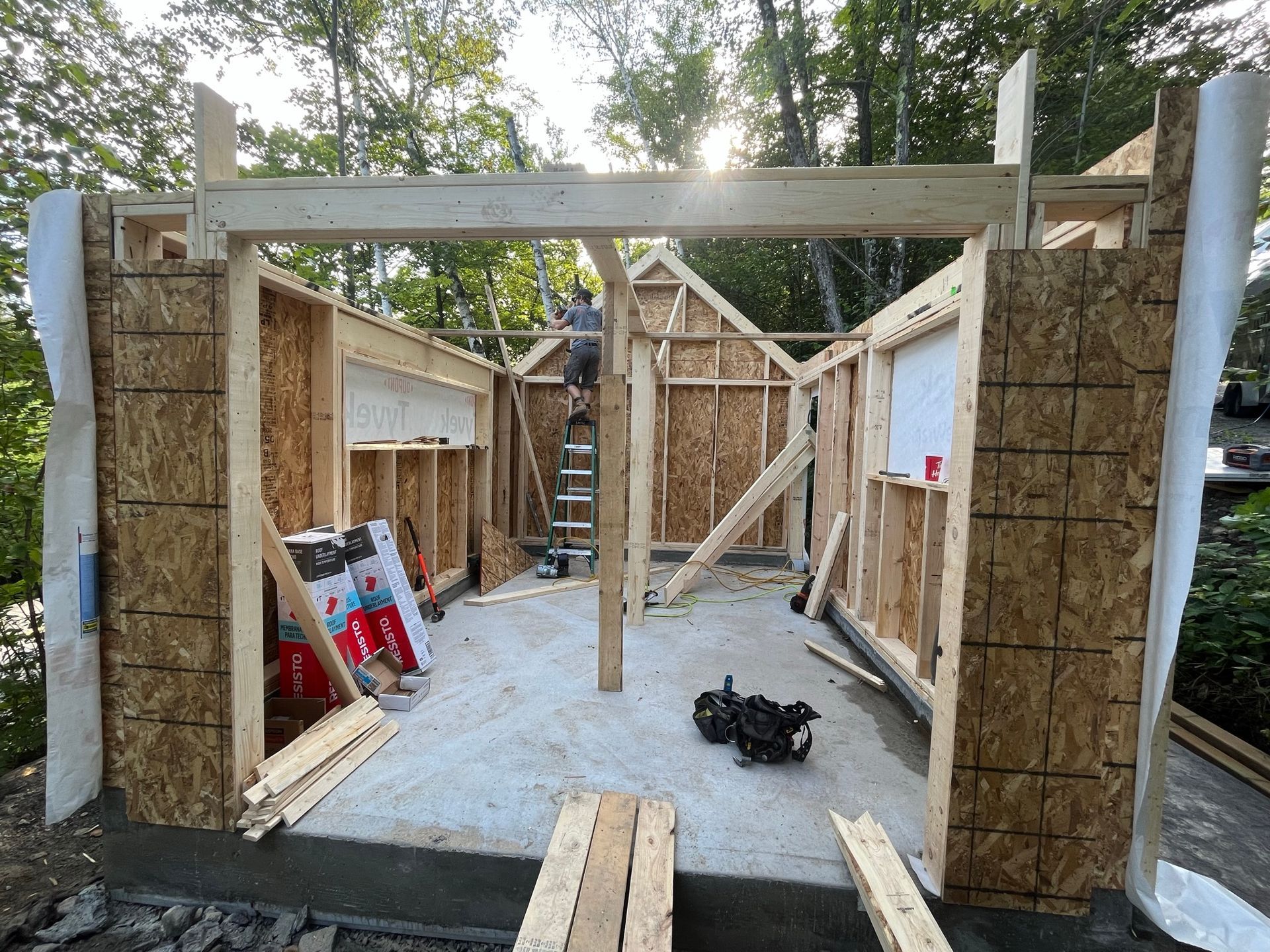 Un homme est debout sur une échelle dans un bâtiment en bois en construction.