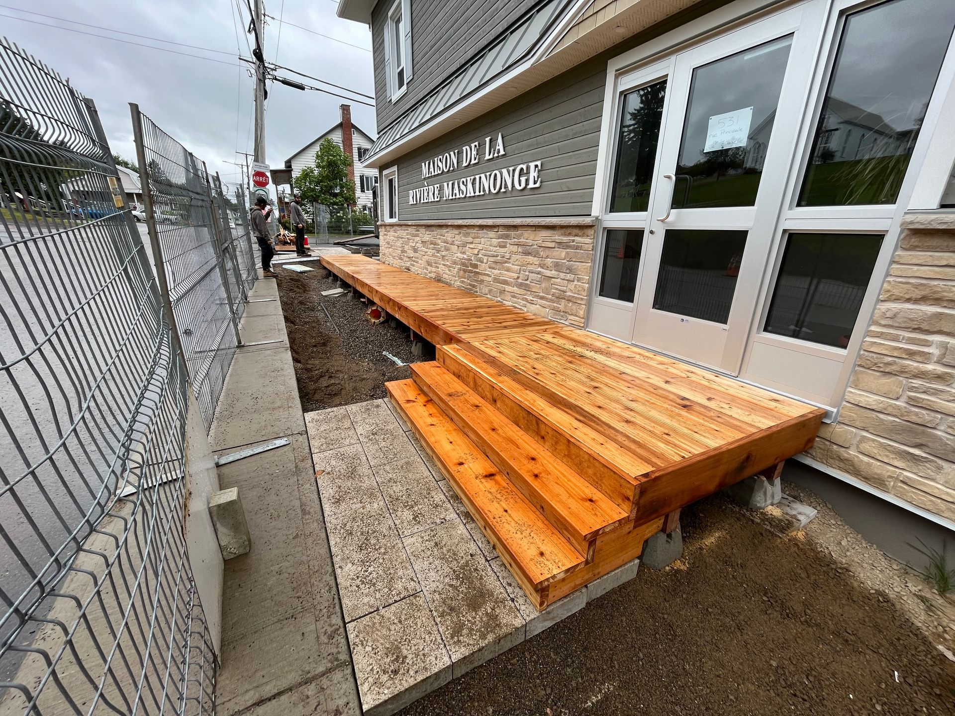 Une terrasse en bois est en cours de construction devant un bâtiment.
