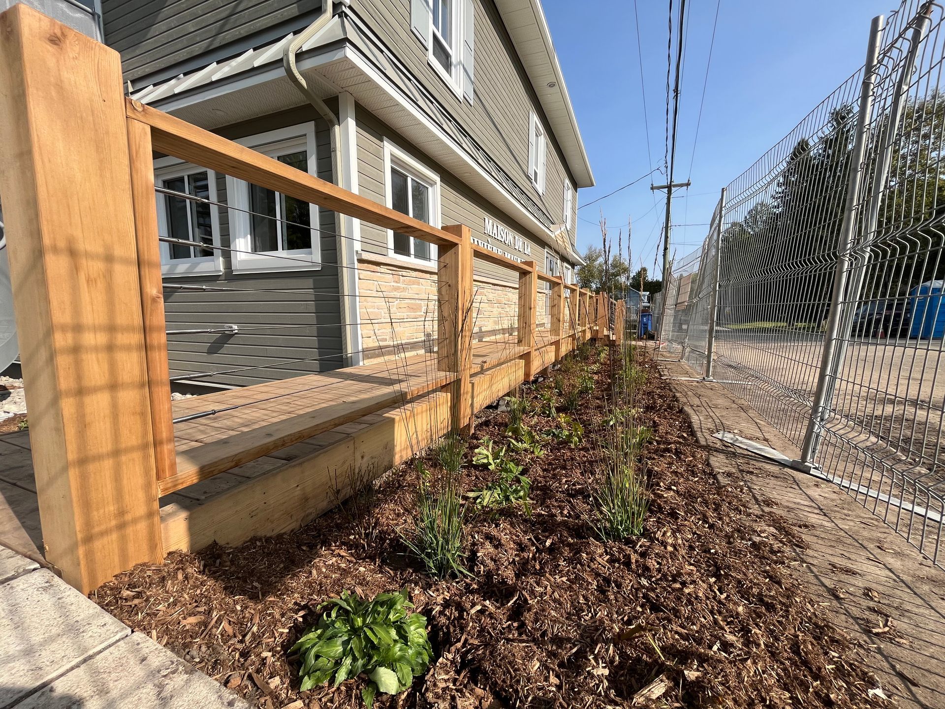 Une clôture en bois entoure un jardin devant une maison.