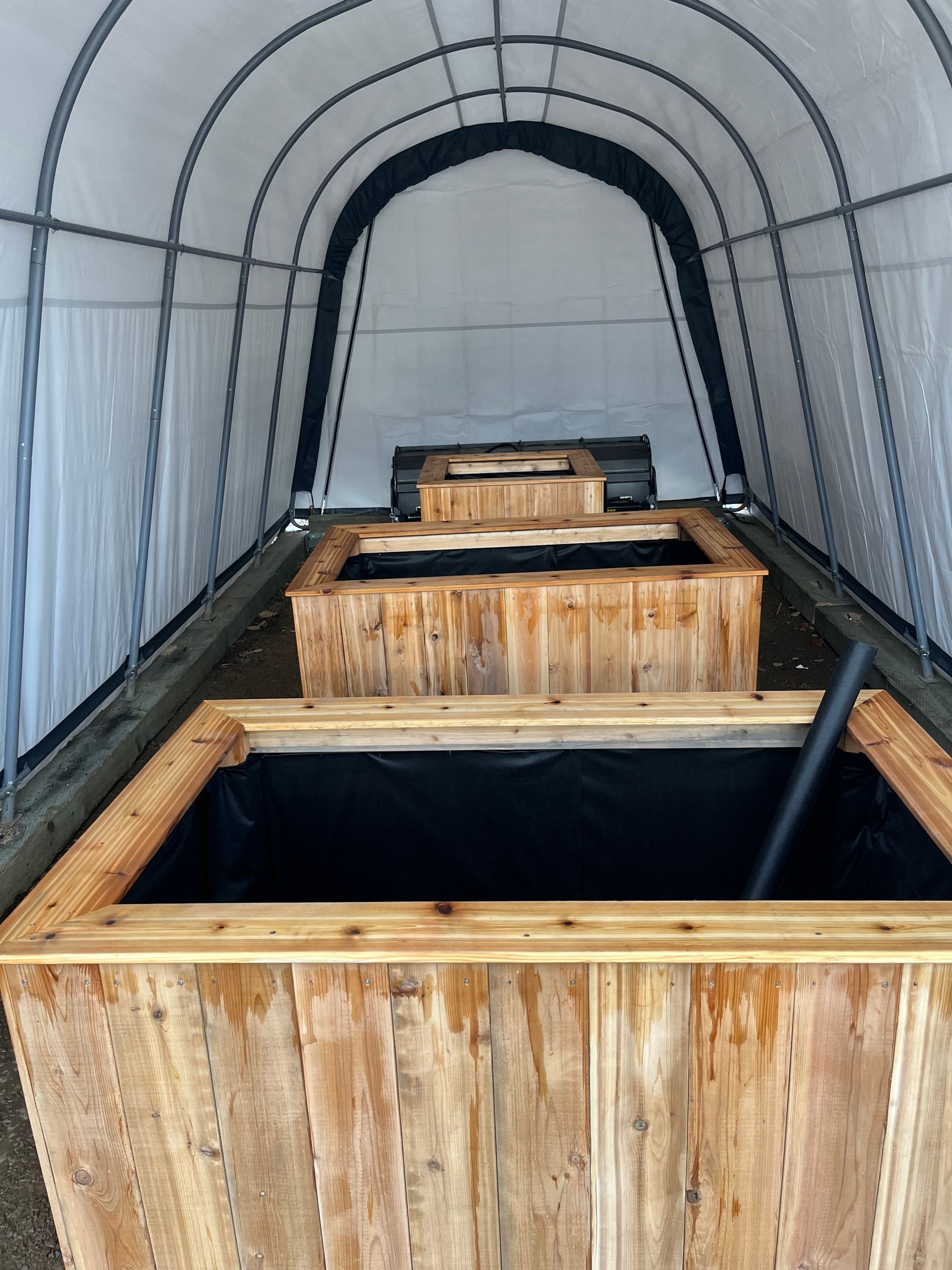 Une rangée de jardinières en bois à l'intérieur d'une tente