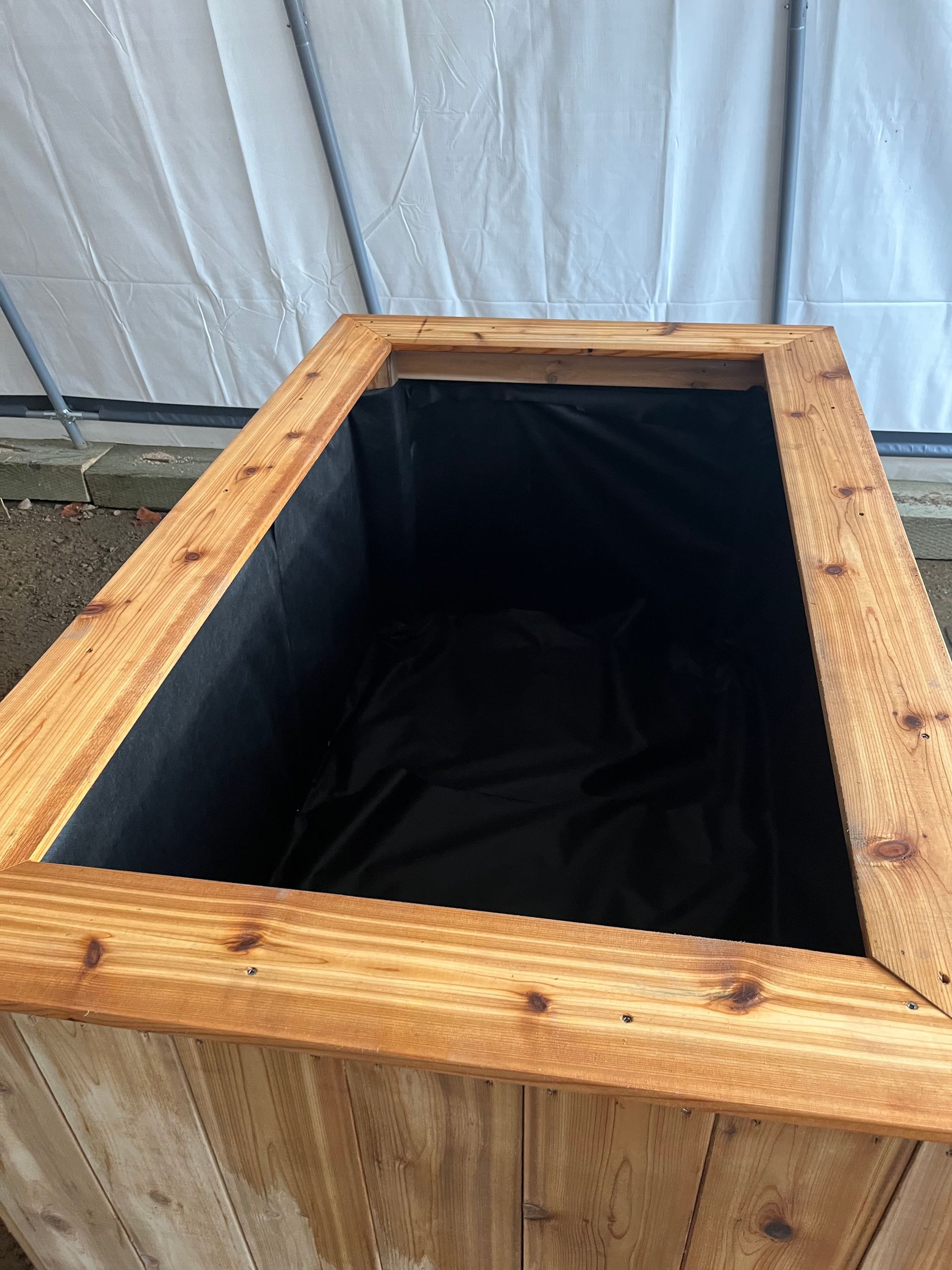 Une jardinière en bois avec une doublure noire à l'intérieur.