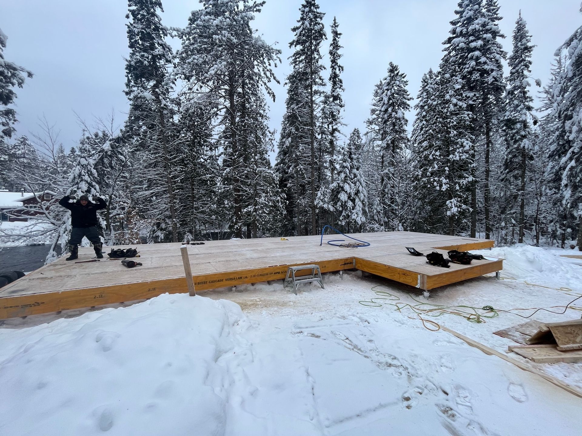 Un homme est debout sur une plate-forme en bois dans la neige.