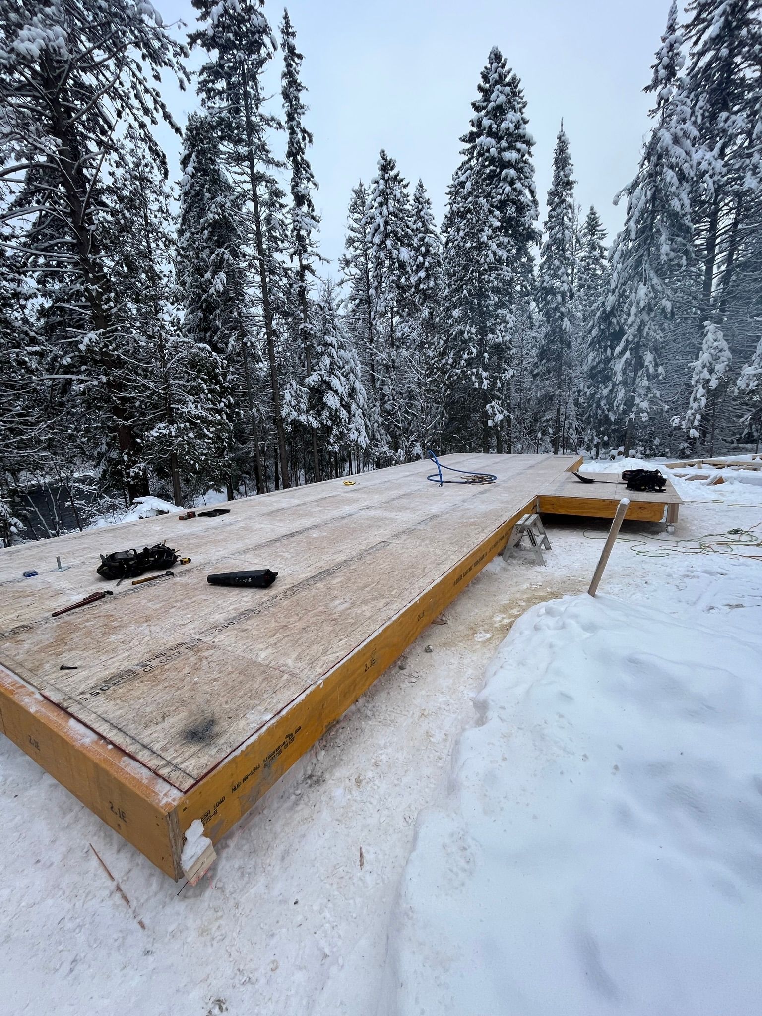 Une terrasse en bois se trouve au milieu d'une forêt enneigée.