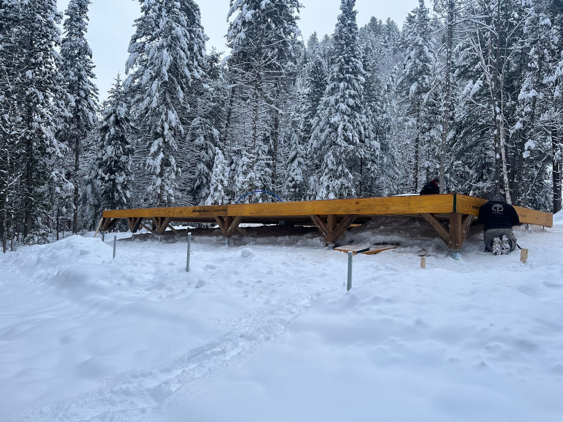 Une grande structure en bois se trouve au milieu d'une forêt enneigée.