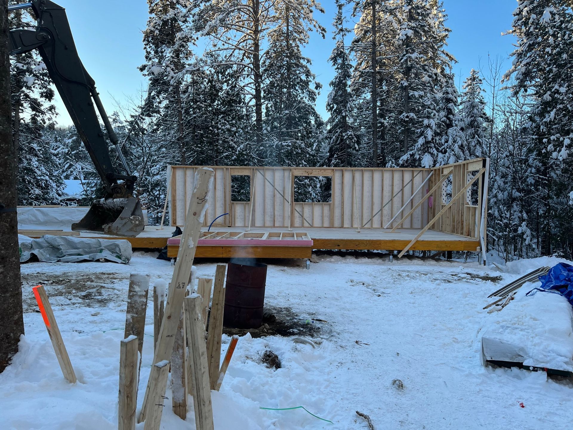 Une maison est en construction dans la neige avec des arbres en arrière-plan