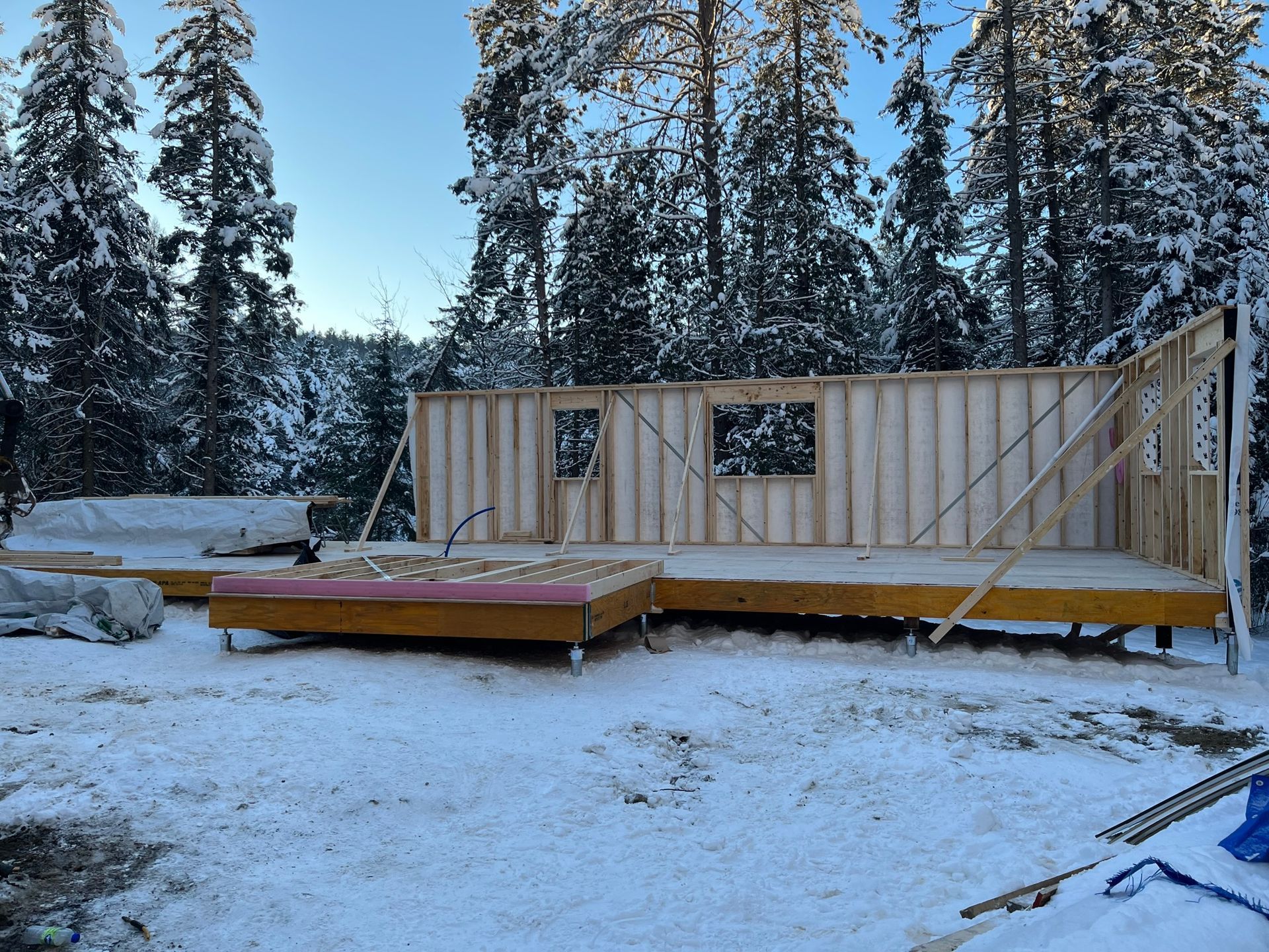 Une maison est en construction dans la neige avec des arbres en arrière-plan