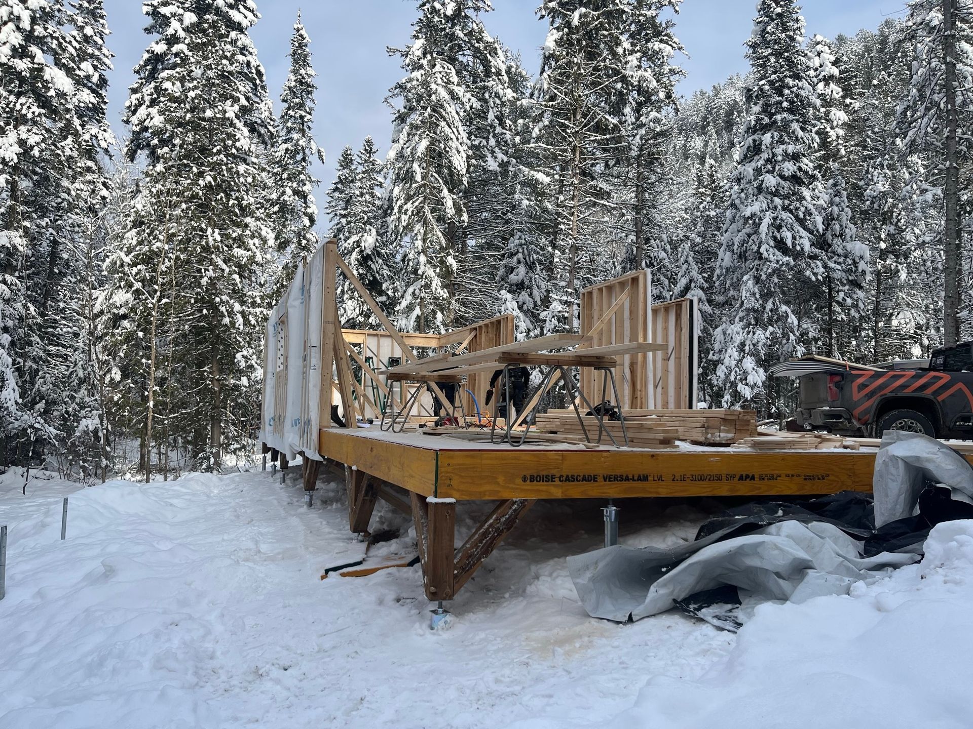 Une structure en bois est en cours de construction dans la neige dans les bois.