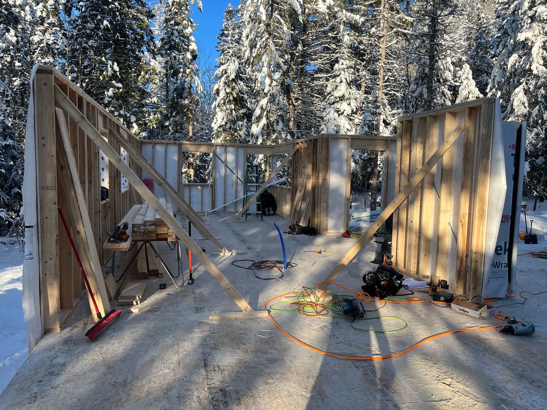 Une structure en bois est en construction au milieu d'une forêt enneigée.