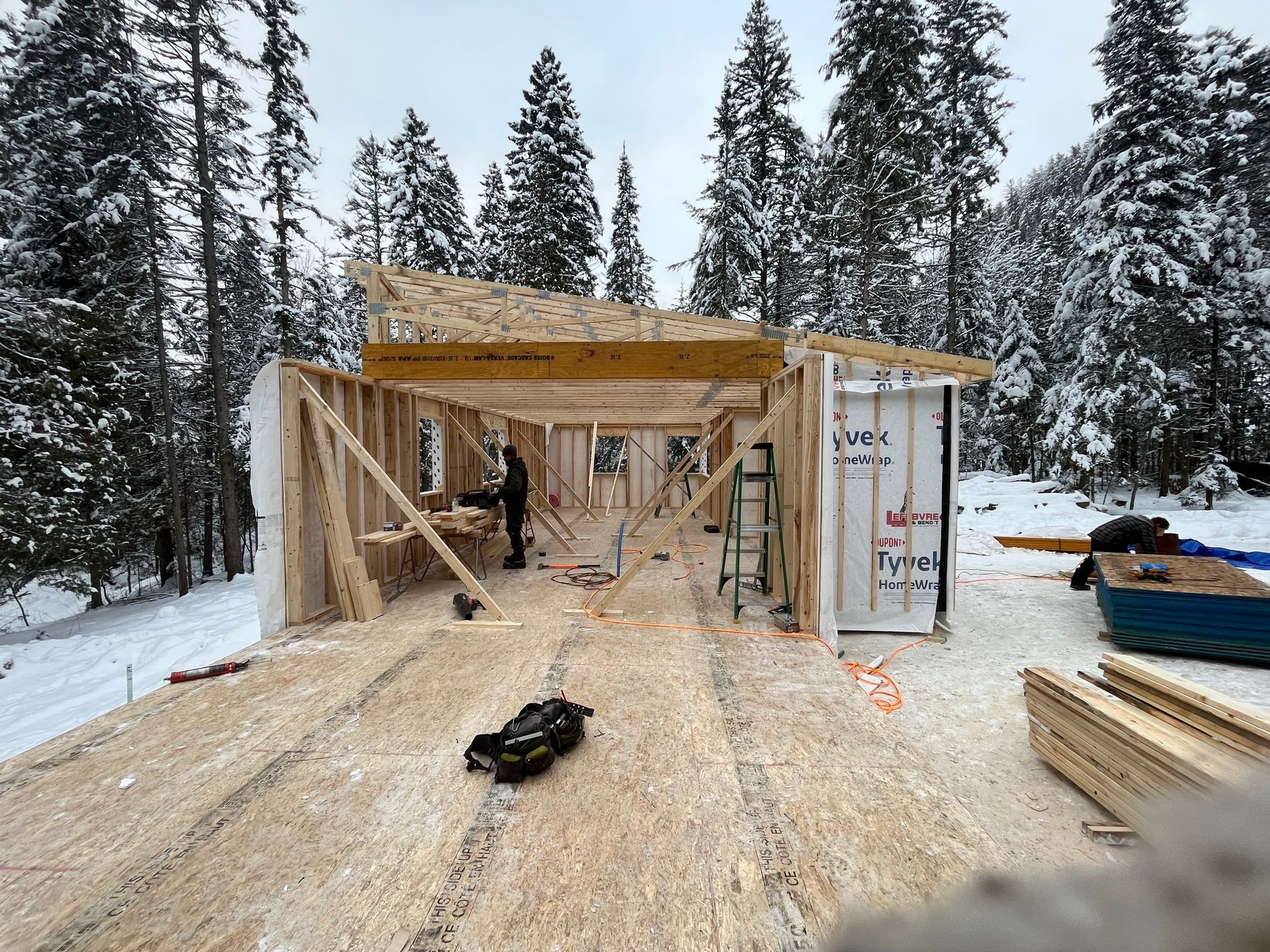 Une maison est en construction dans la neige dans les bois.