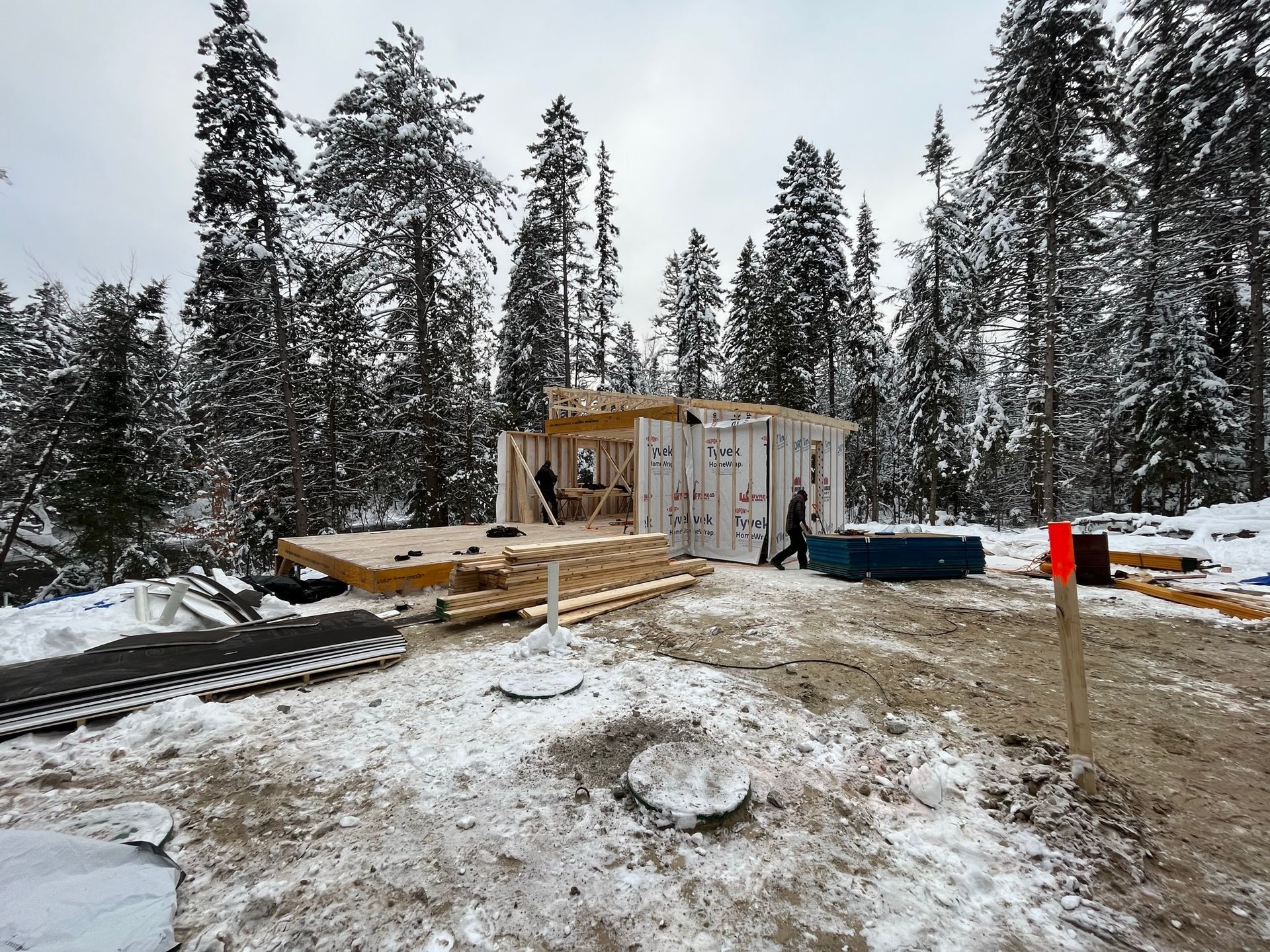 Une maison est en construction au milieu d'une forêt enneigée.