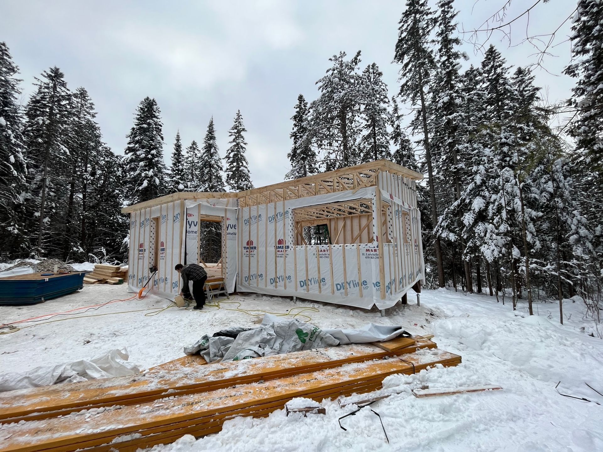 Une maison est en construction dans la neige dans les bois.