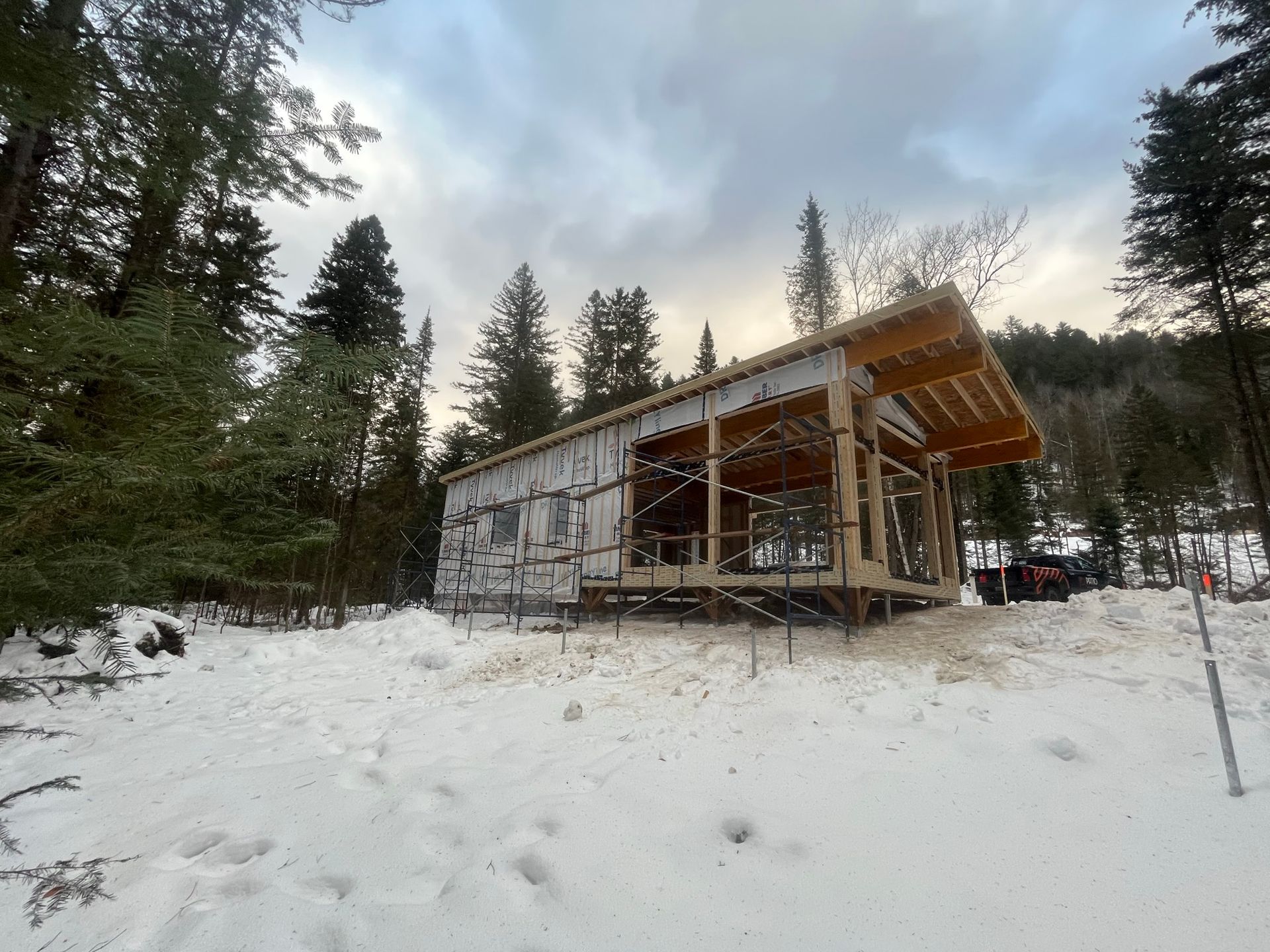 Une maison est en construction dans la neige au milieu d'une forêt.