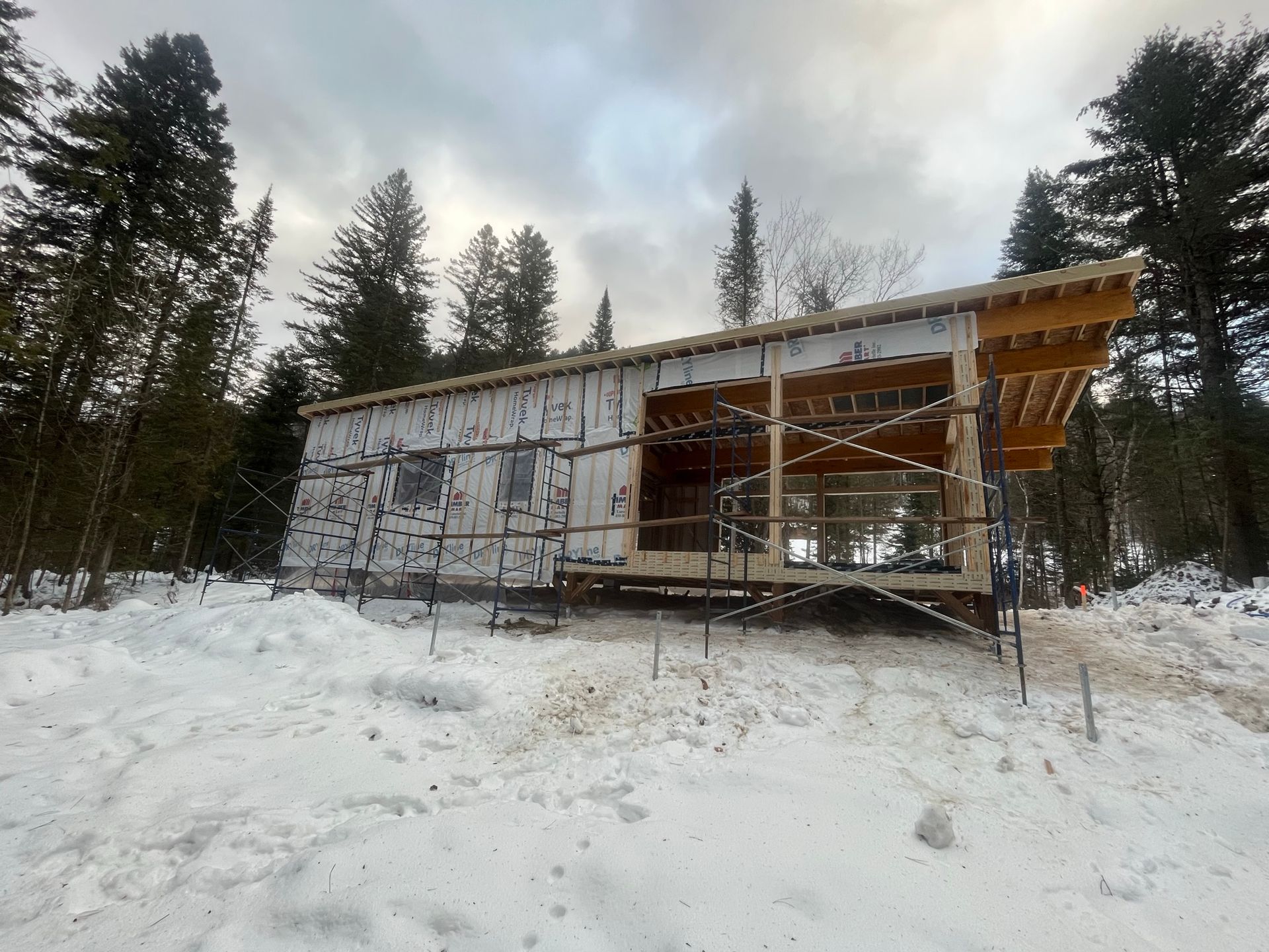 Une maison est en construction dans la neige au milieu d'une forêt.