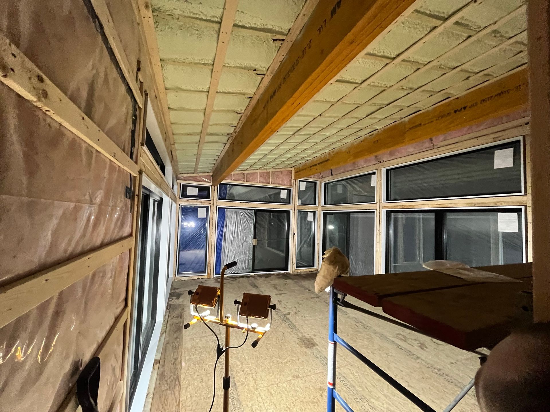 Une grande pièce avec beaucoup de fenêtres et un plafond en bois.