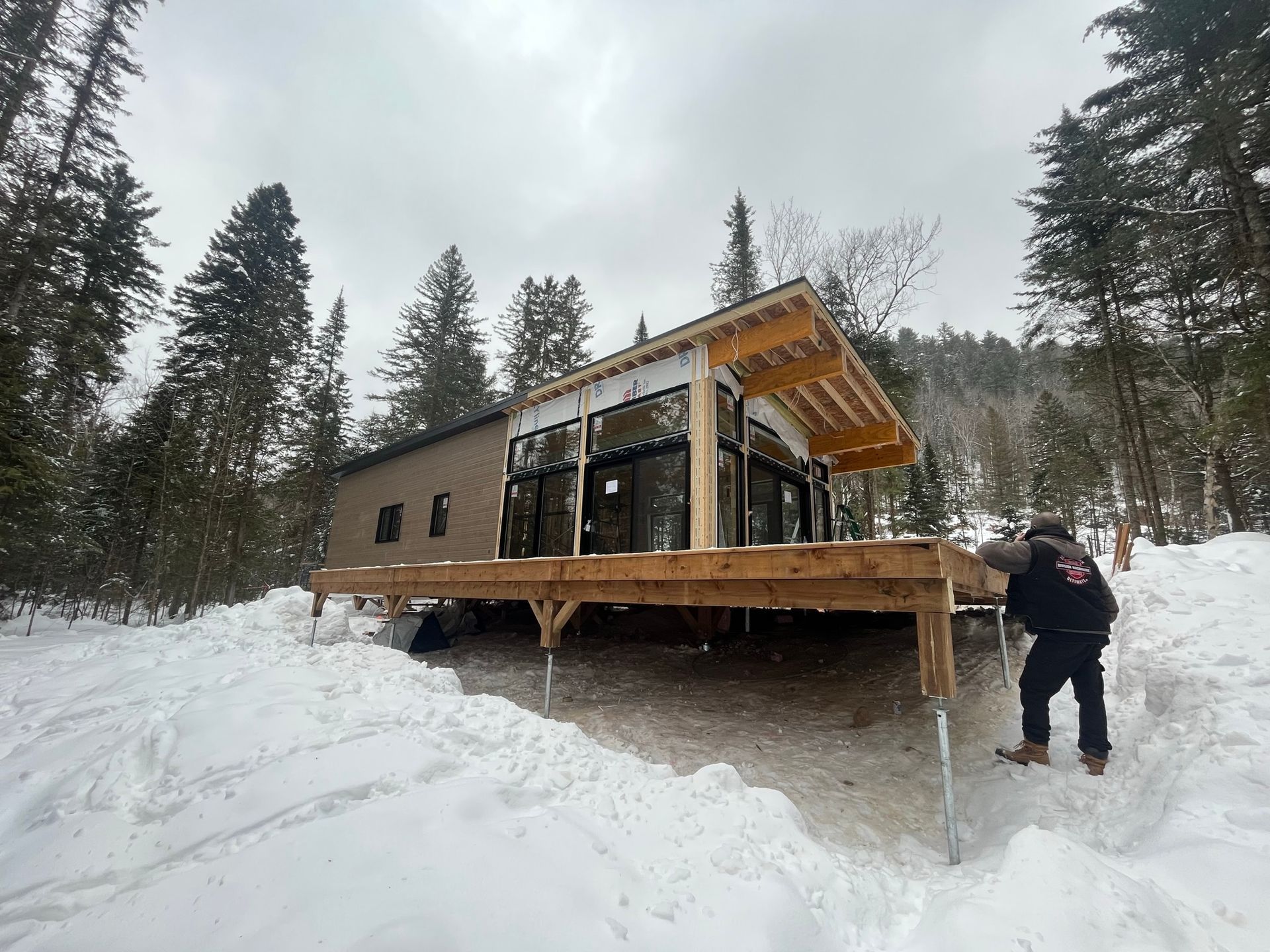 Un homme se tient devant une maison dans la neige.