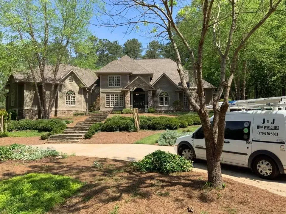 Suburban house with stone facade and front yard, partly blocked by a white service van in the driveway.