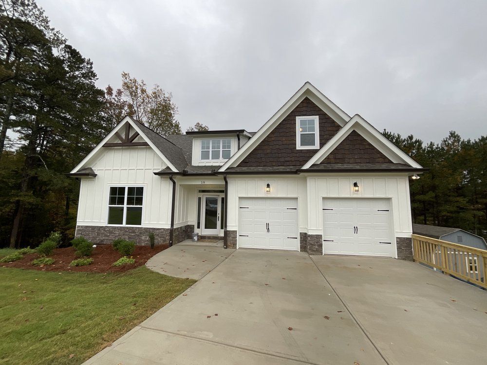 Suburban house with two-car garage, driveway, and front lawn under a cloudy sky