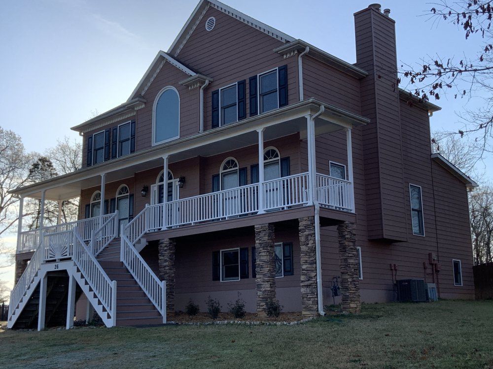 Two-story brick house with white porch railings and a staircase, viewed from the front yard