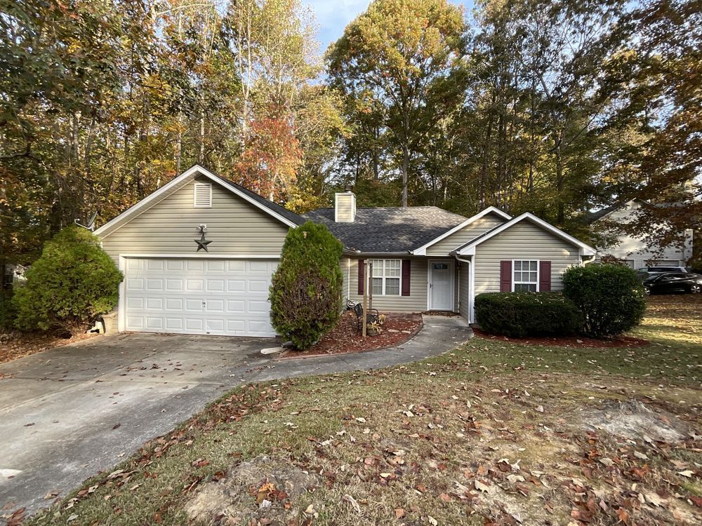 Suburban house with two-car garage, brick facade, and autumn trees in front yard
