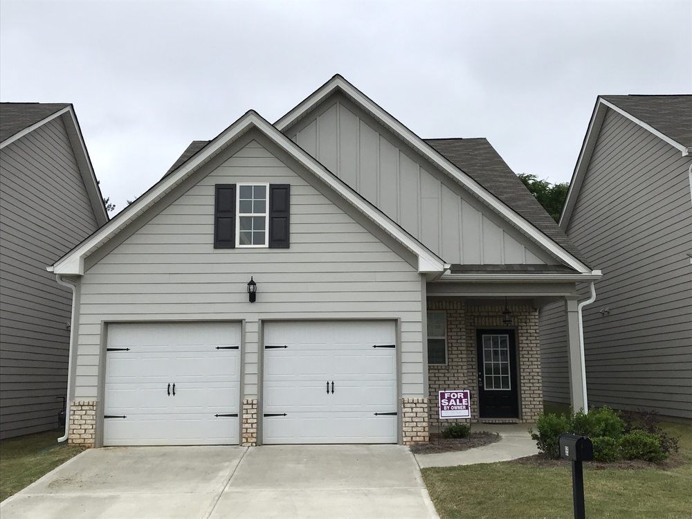 Single-story gray house with double white garage doors and a small front porch.