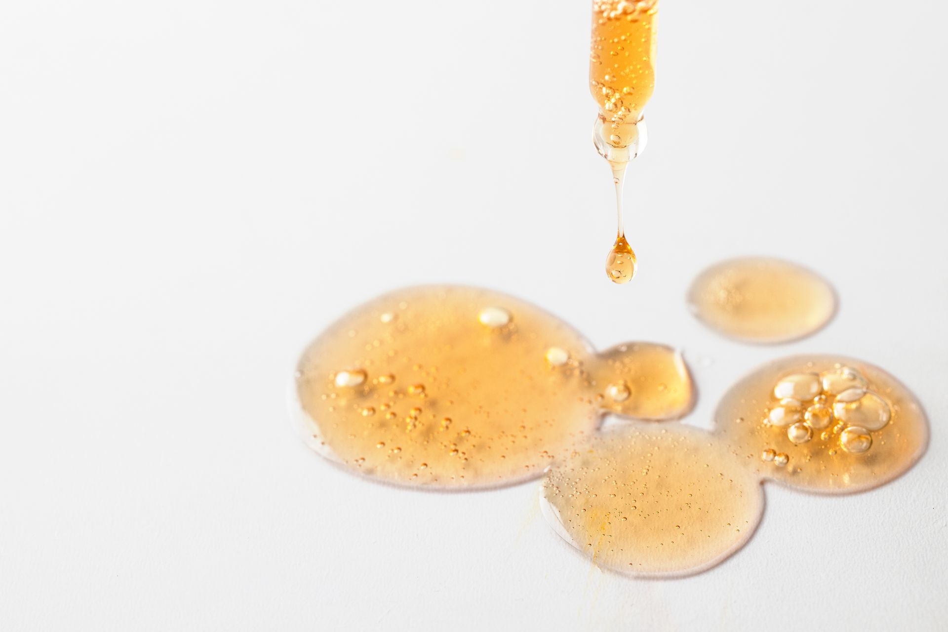 Consistenza fluida di un siero illuminante su superficie neutra — cosmetica professionale