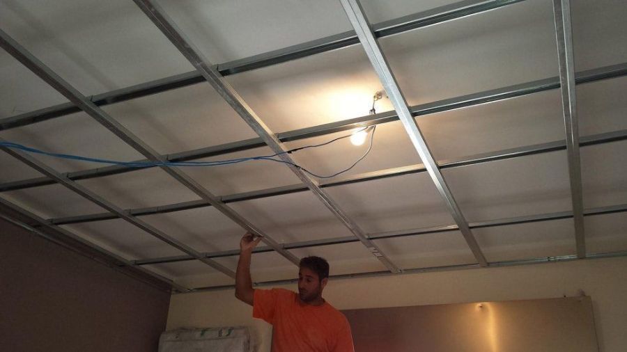 L'uomo installa una griglia sul soffitto con lampada; interno.