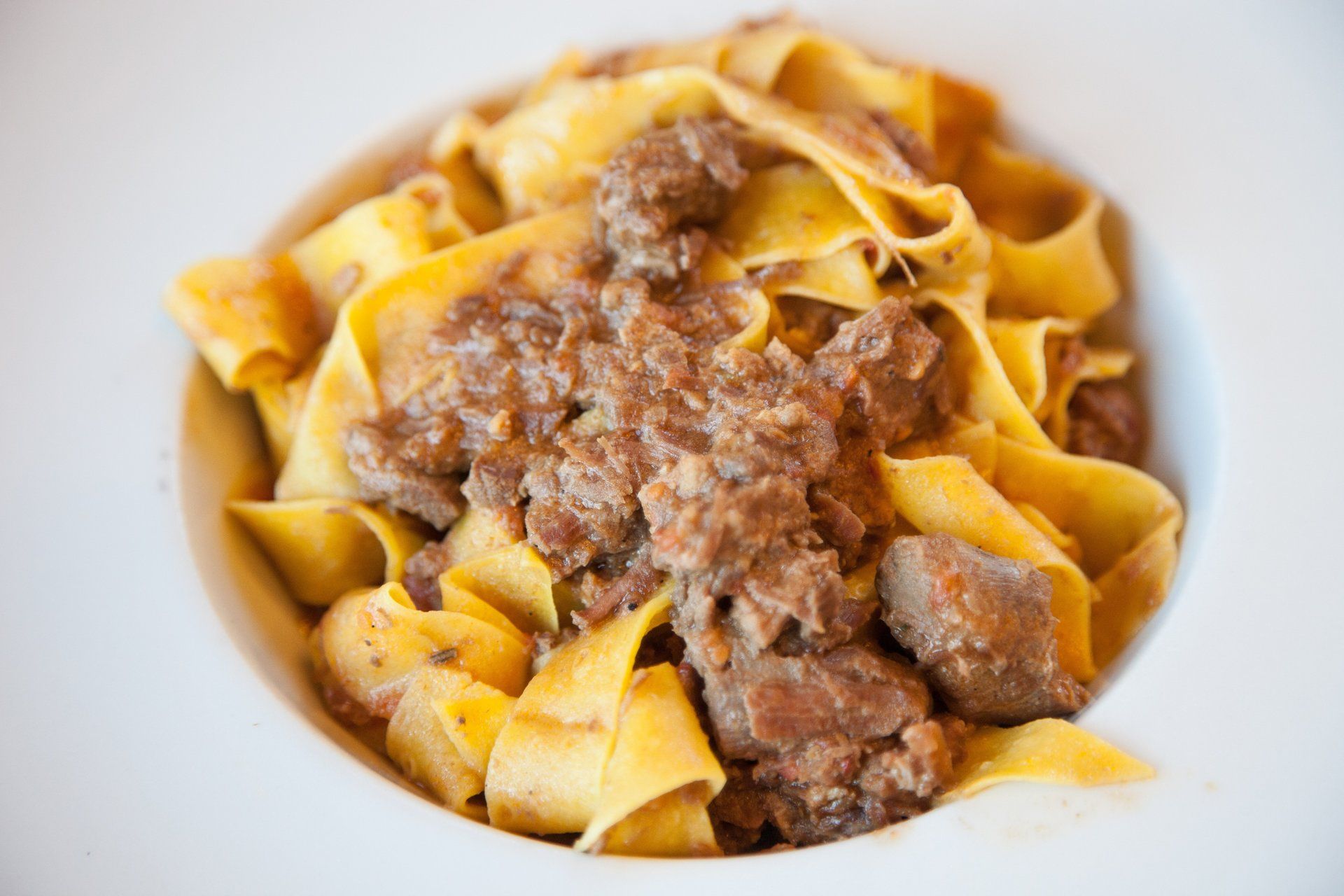 Pappardelle al ragù in una ciotola bianca.