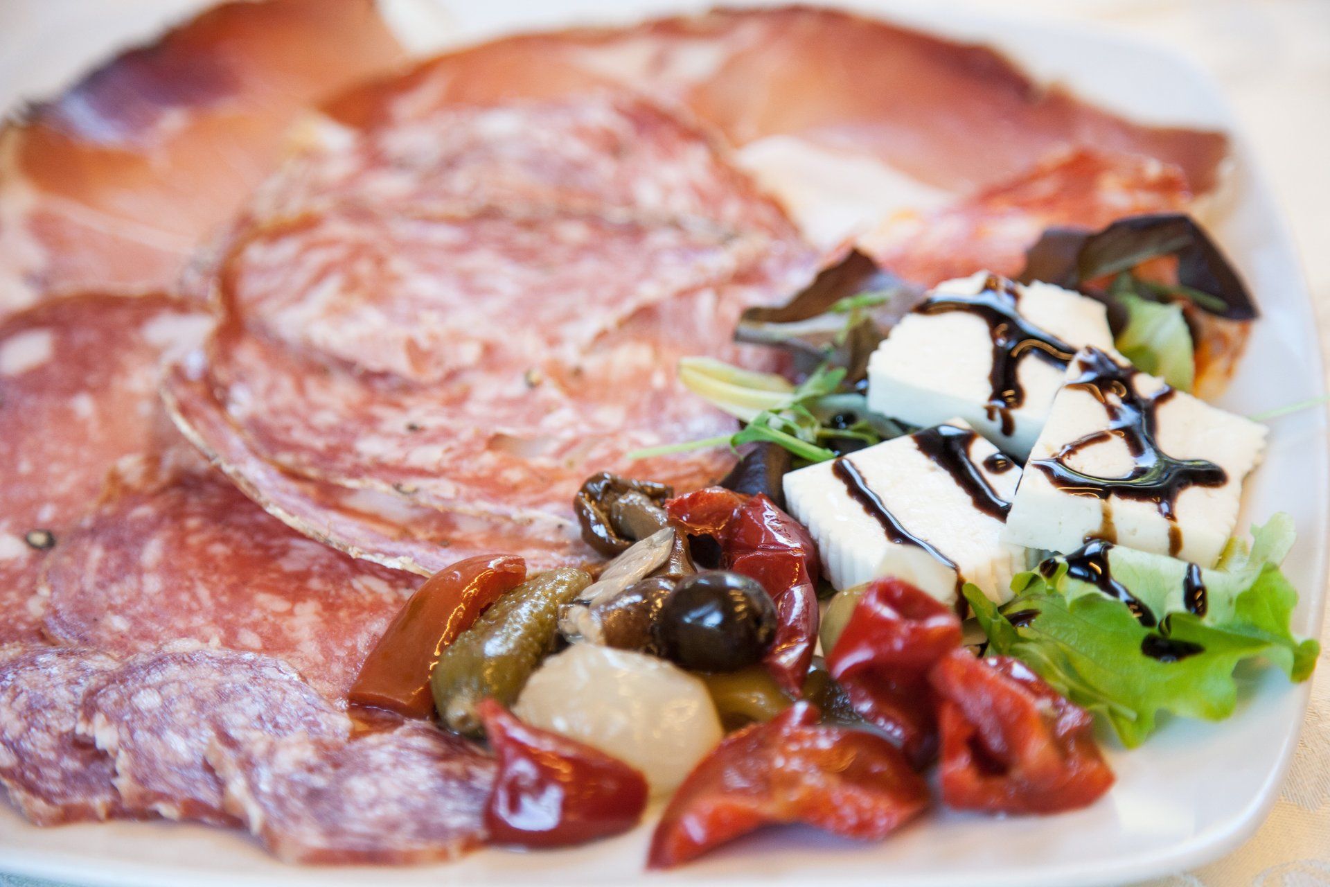 Piatto di salumi con affettati, formaggio, olive e peperoni arrostiti.