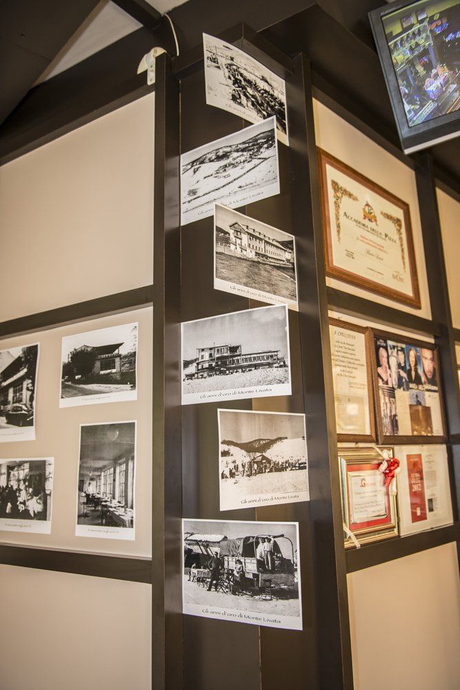 Espositore angolare a parete con vecchie fotografie in bianco e nero e documenti incorniciati.