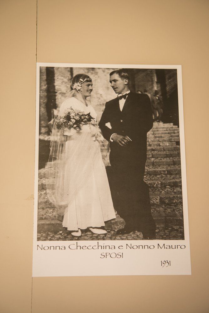 Foto di matrimonio vintage: sposa con velo e bouquet, sposo in smoking, in piedi sui gradini, tonalità seppia.