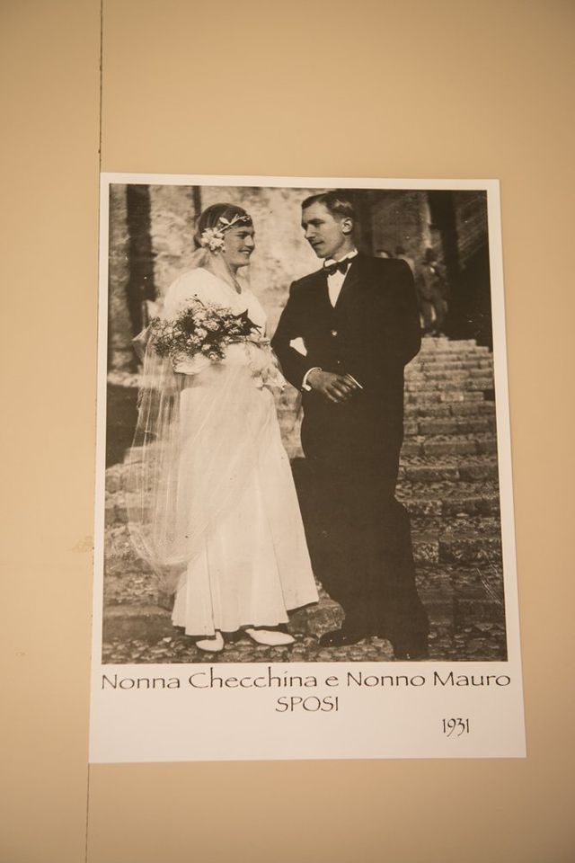 Foto di matrimonio vintage: sposa con velo e bouquet, sposo in smoking, in piedi sui gradini, tonalità seppia.