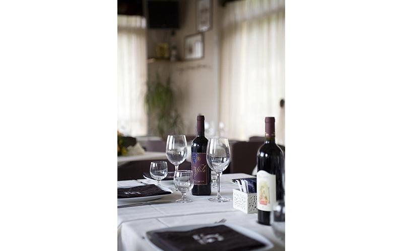 Tavolo apparecchiato con bottiglie di vino, bicchieri e menu in un ristorante.