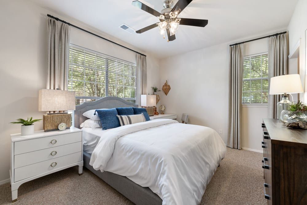 a bedroom with a bed, dresser, nightstand, and ceiling fan at Marquis Carmel Valley in Charlotte, NC.
