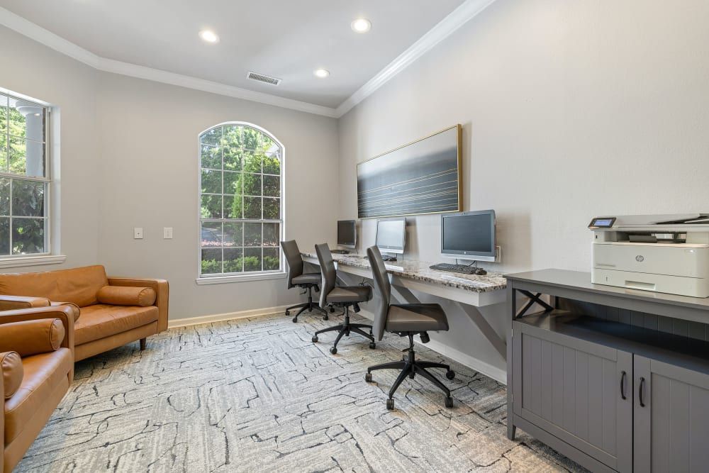 a room with a couch, chairs, computers, and a printer at Marquis Carmel Valley in Charlotte, NC.