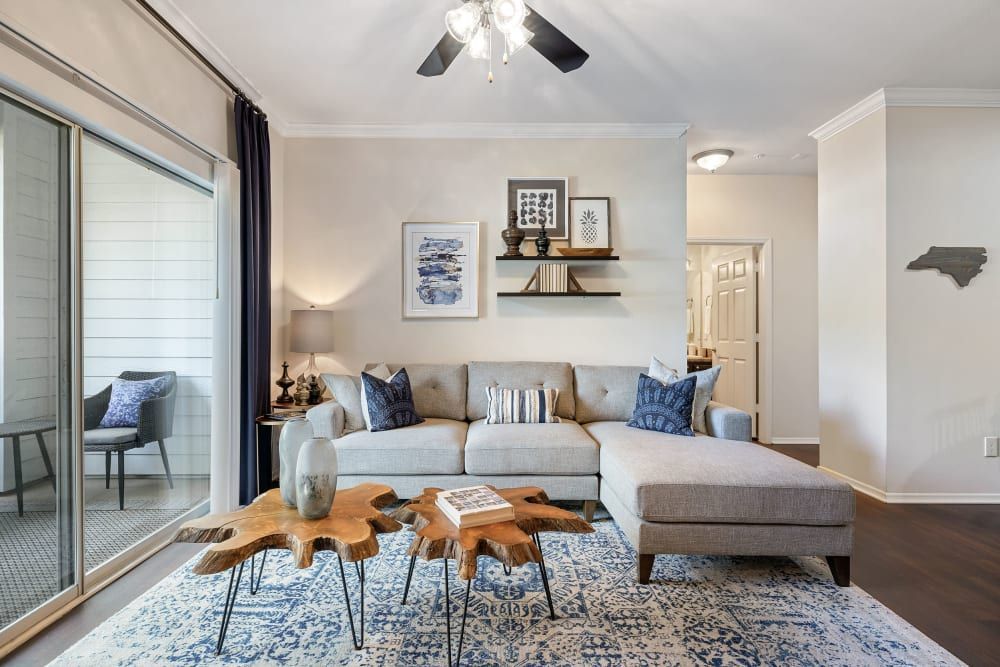 a living room with a sectional couch, two coffee tables, and a ceiling fan at Marquis Carmel Valley in Charlotte, NC.