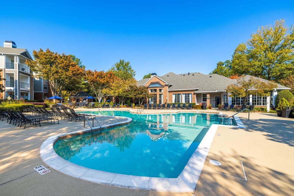 a large swimming pool is surrounded by chairs and a building at Marquis Carmel Valley in Charlotte, NC.