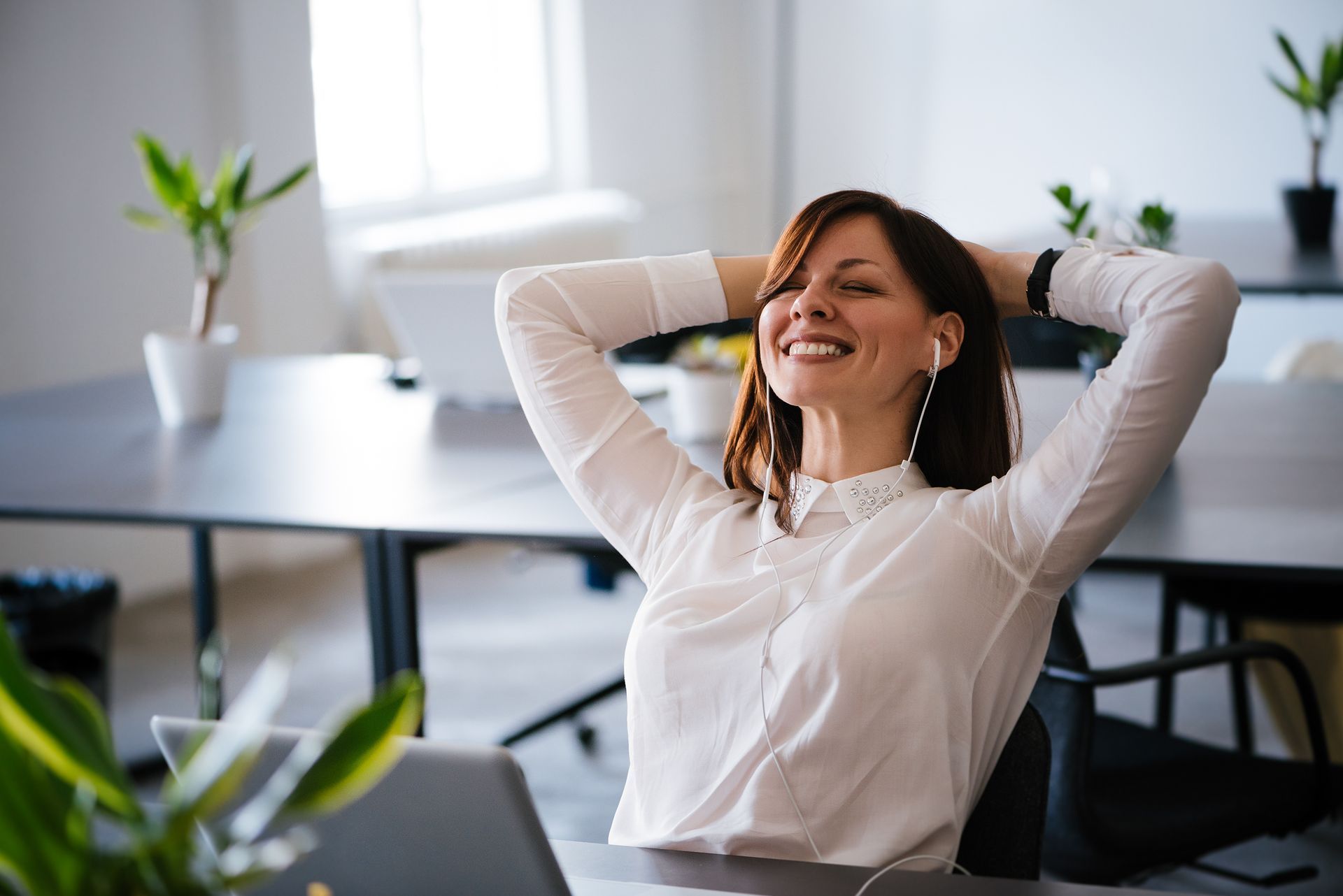 Une femme est assise à un bureau avec ses mains derrière sa tête.