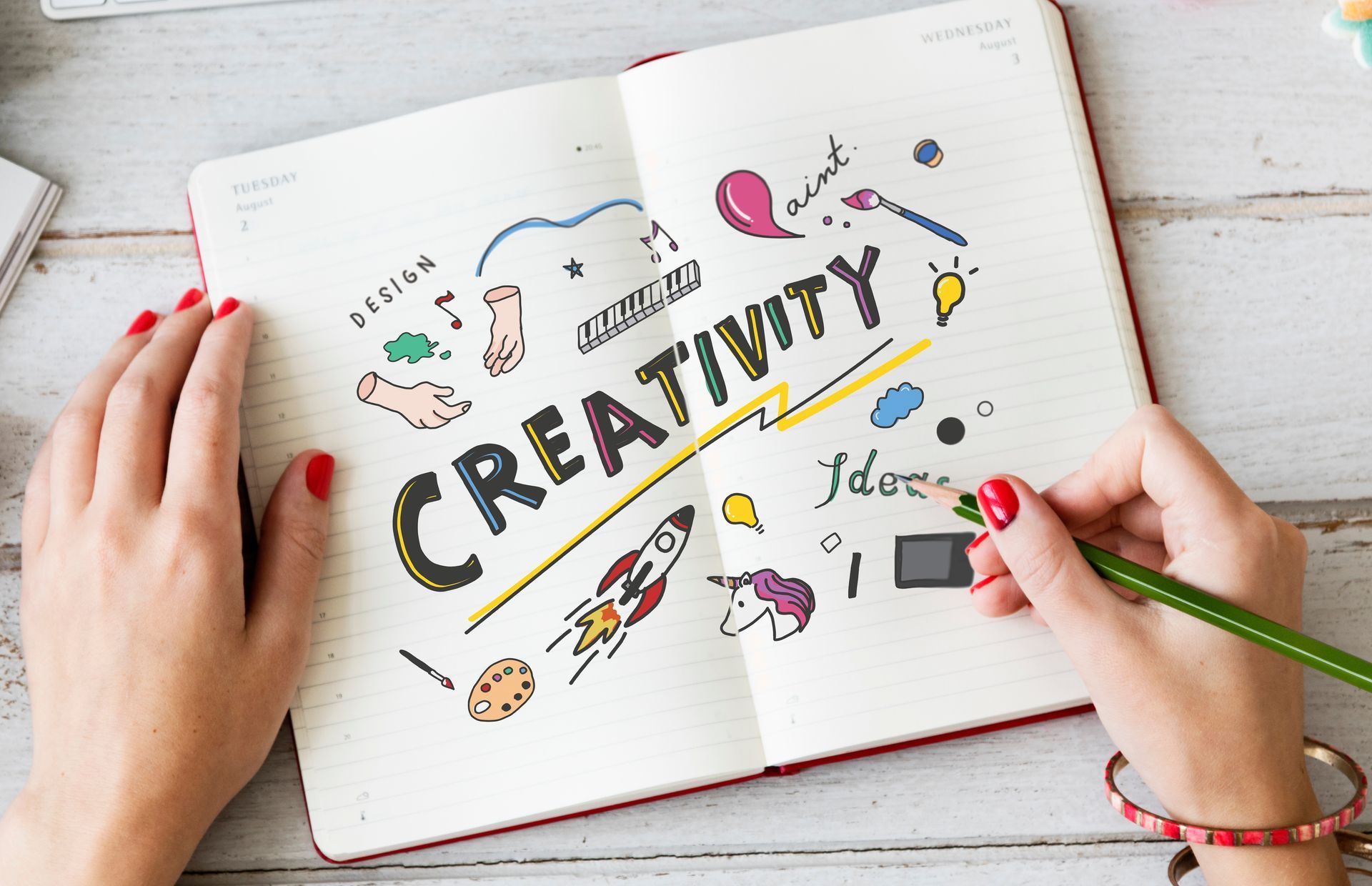 Une personne écrit dans un cahier sur lequel est écrit créativité