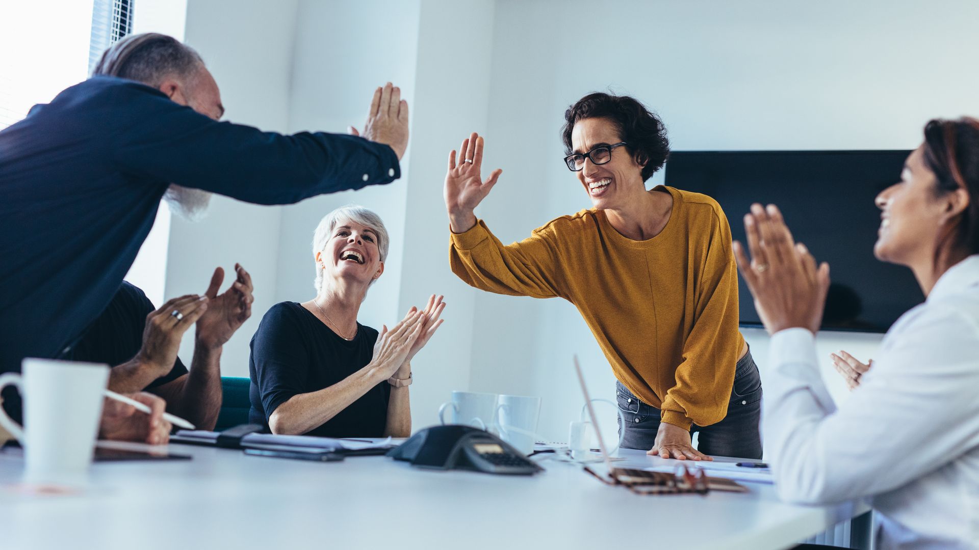 Un groupe de personnes sont assises autour d'une table et se font un high five.