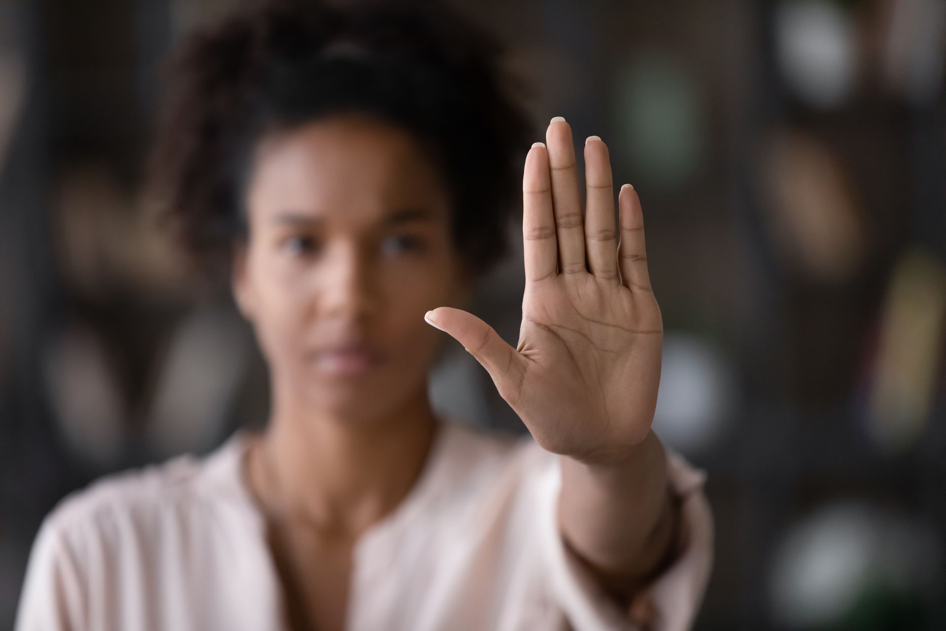 Une femme fait un signe d'arrêt avec sa main.