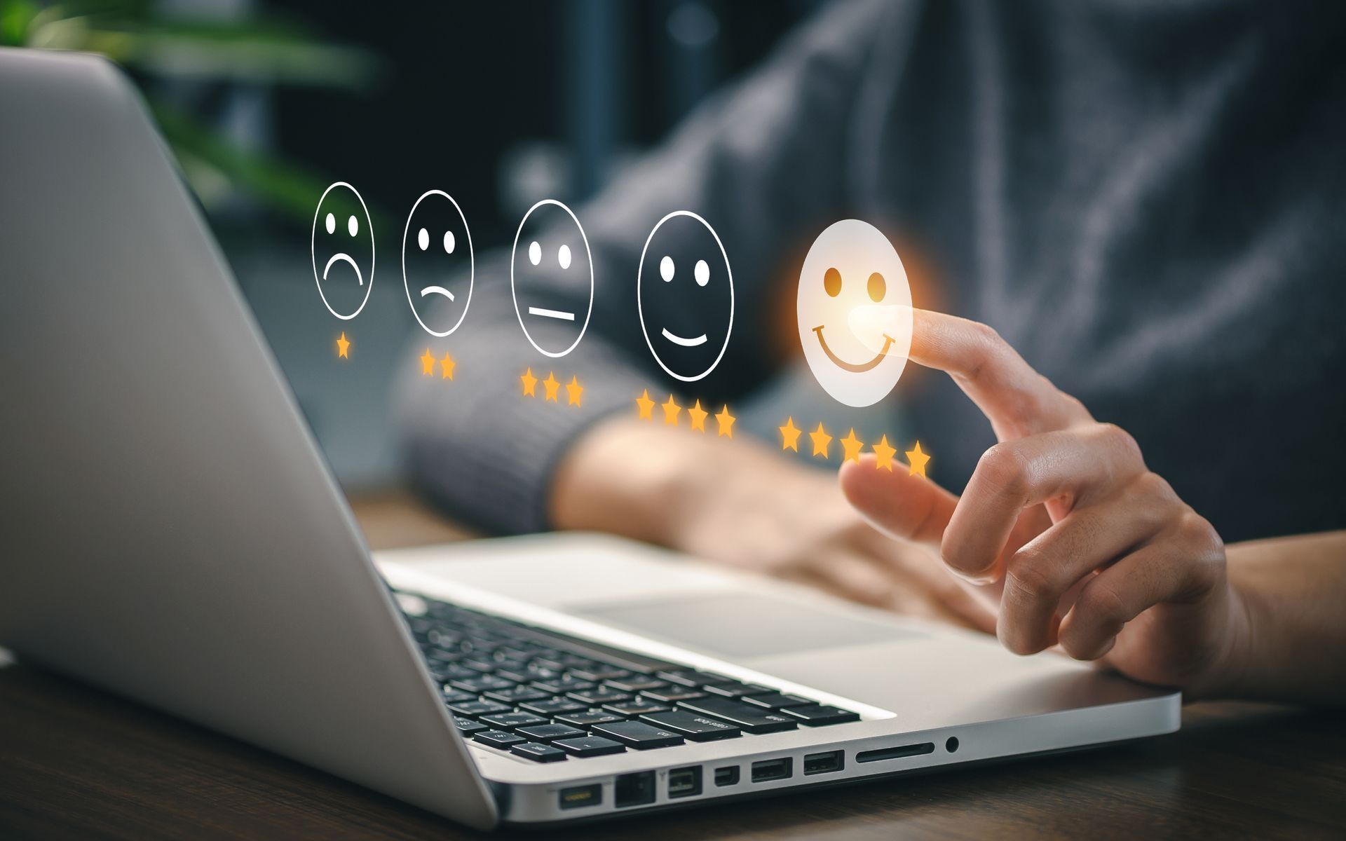 Une personne utilise un ordinateur portable et pointe un visage souriant.