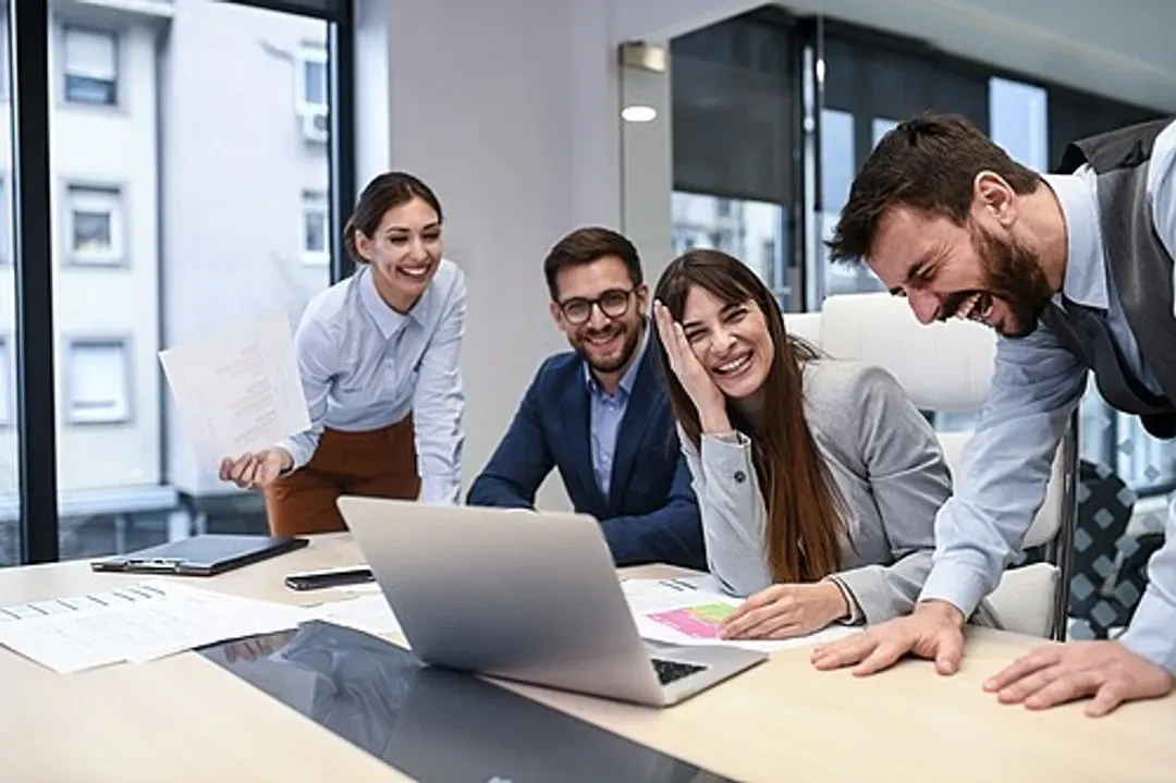 Un groupe de personnes sont assises autour d'une table et regardent un ordinateur portable.