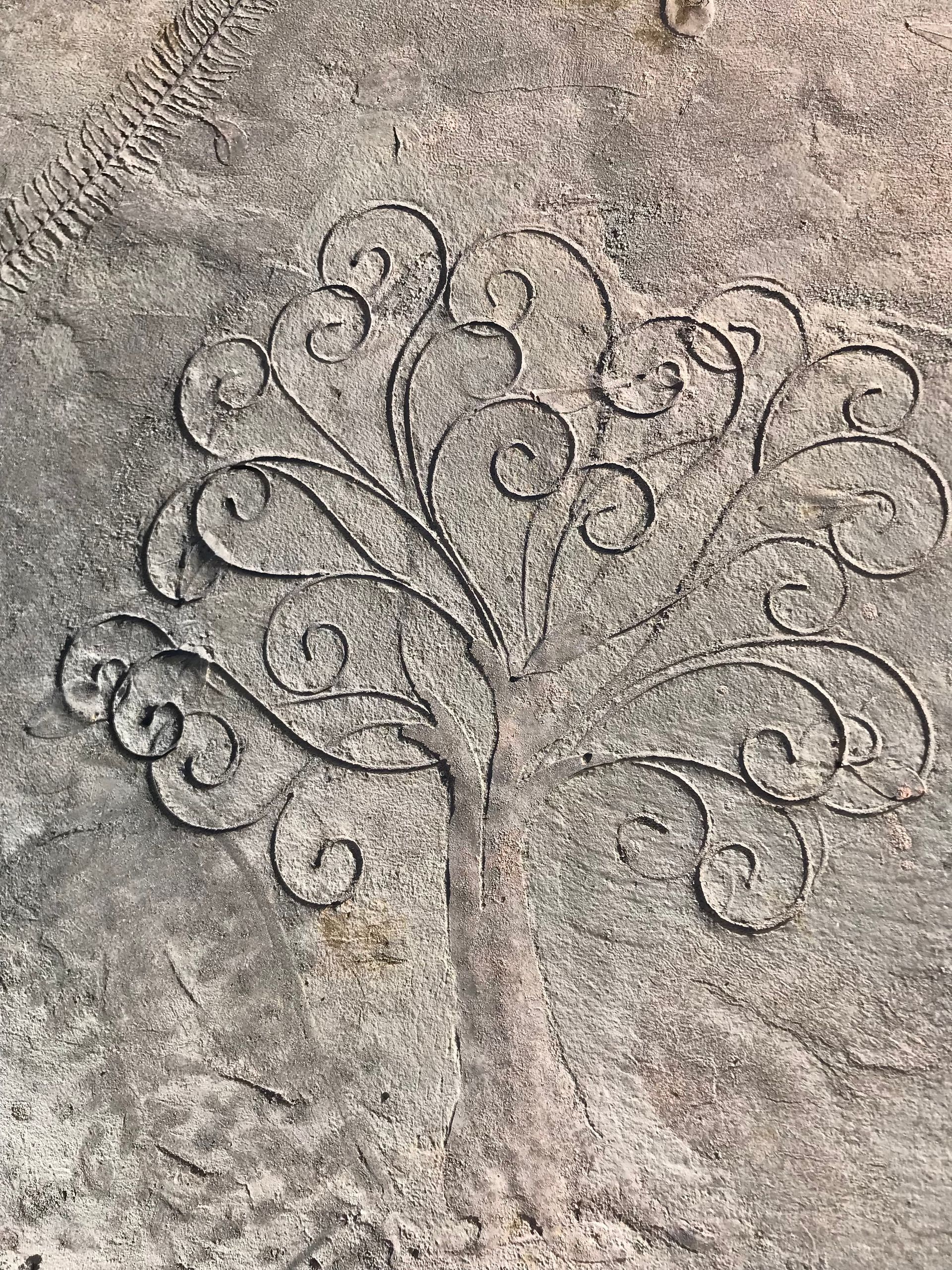 A close up of a stone carving of a peacock on the ground.